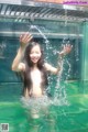 A woman in a swimming pool with water splashing around her.