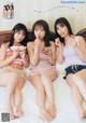 Three young women sitting on a bed eating food.