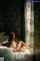 A woman sitting on a bed in a white lingerie.