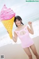 A woman in a pink bathing suit holding an ice cream cone.