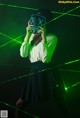 A woman in a white shirt and black skirt holding a green light up mask.